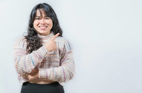 Beautiful asian woman pointing and presenting something, isolated. Cheerful asian girl pointing at