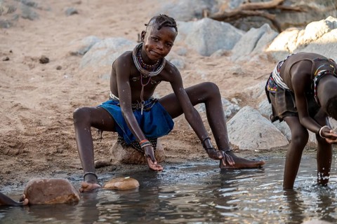 Himba child washing with water on a river, traditional Himba, Kaokoveld, Kunene, Namibia