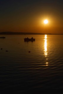 Sunset over the Steinhuder Meer with boat and reflections, quiet atmosphere, Steinhude