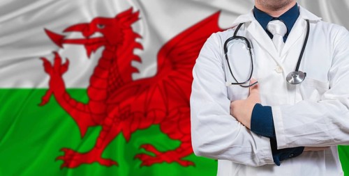 Male doctor with stethoscope on Wales flag. Doctor holding stethoscope on Wales flag