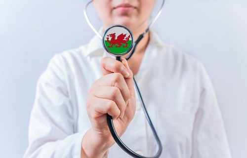 Female doctor holding stethoscope with Wales flag. National health system of Wales