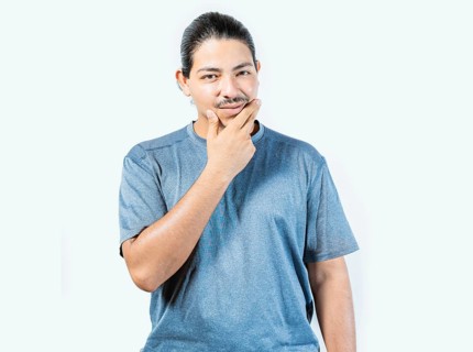 Pensive person rubbing chin with doubtful expression. Thoughtful young man rubbing his chin looking