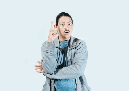Surprised guy pointing a promotion up isolated. Surprised asian man pointing a discount up on