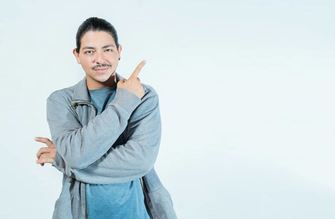 Latin guy pointing an advertising to side isolated. Smiling people pointing a banner on blank space