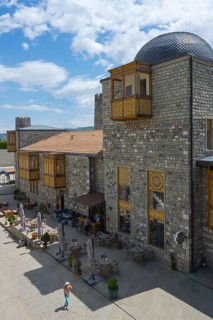 Stone building with decorative wood paneling and dome surrounded by blue sky, Rabati Fortress,