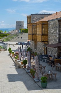 Outdoor terrace with decorated wooden areas and a view of a tower in the blue sky, Rabati Fortress,