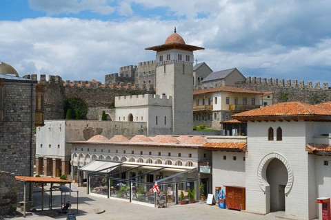 Castle complex with tower-like building and Mediterranean elements in front of a stone wall, Rabati