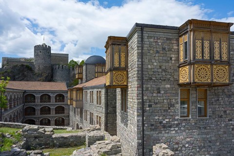 Historic buildings with towers and detailed wooden elements under a blue sky, Rabati Fortress,