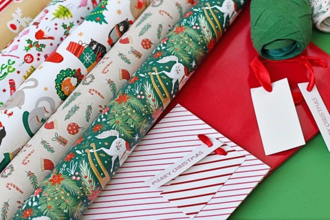 Close up of Christmas wrapping material like paper, bags and ribbons on green background