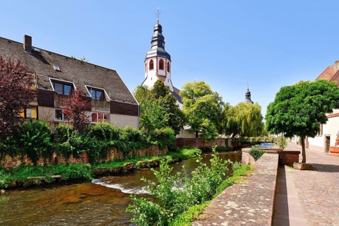 Ettlingen, Germany - August 13th 2025: Alb brook in historic center with church tower of Roman