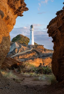 Castlepoint lighthouse on a rock, sea, sunrise. Castlepoint, Wairarapa Coast, Wellington Region,