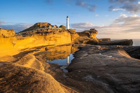 Castlepoint lighthouse on a rock, sea, sunrise. Castlepoint, Wairarapa Coast, Wellington Region,