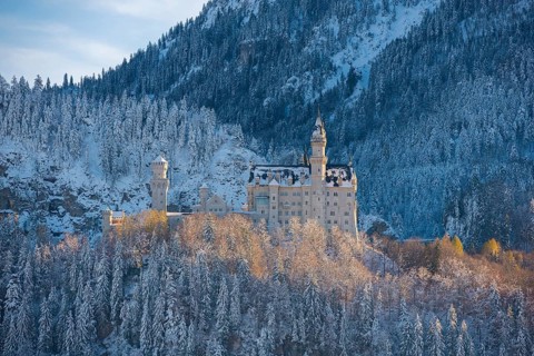 Historic Neuschwanstein Castle in winter, nestled in an idyllic, snow-covered mountain landscape,