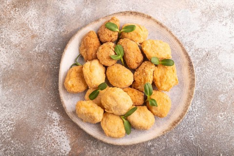 Fried crispy Chicken Nuggets with ketchup, microgreen on brown concrete background. top view, flat
