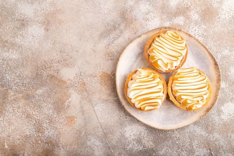 French lemon tart with meringue on brown concrete background, top view, flat lay, copy space