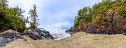 Panoramic view of a secluded beach and inlet in tofino, vancouver island, featuring dramatic rock