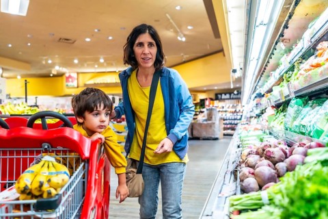 Mother and son shopping together for fresh produce in a supermarket, selecting healthy food options
