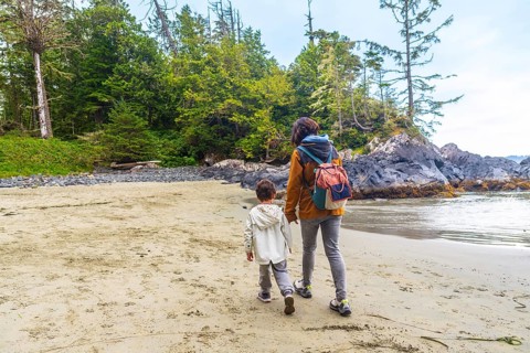 Mother and son enjoying a leisurely stroll along a beautiful sandy beach in tofino, british