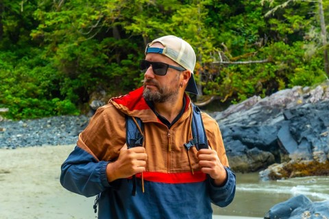 Male tourist wearing sunglasses and a baseball cap, exploring the beautiful beaches and lush