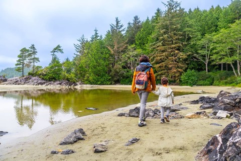 Mother and daughter, hand in hand, enjoy a peaceful stroll along mackenzie beach in tofino, british
