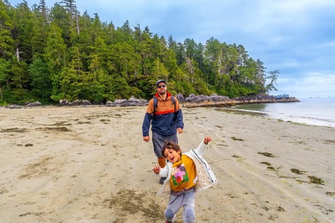 Father and son are walking on chesterman beach in tofino, british columbia, canada, enjoying the