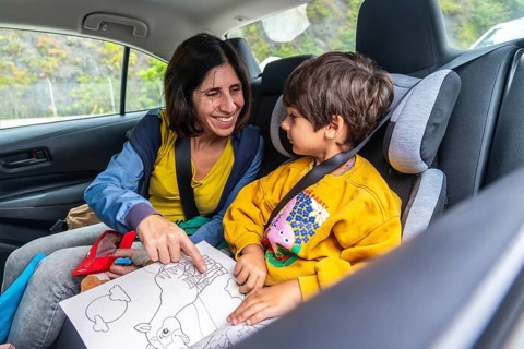 Mother and son sharing joyful moments during a road trip, reading a colorful children's book