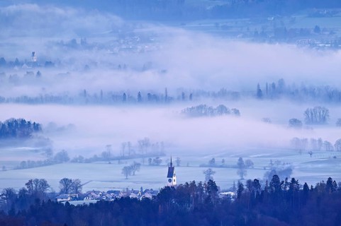 Meadows and trees in the morning fog and the church in the foreground, Reusstal, Merenschwand,