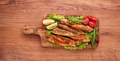 Fried crispy red mullet fish, on a wooden chopping board, with lime, no people