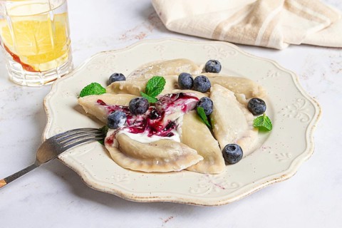 Handmade dumplings filled with sweet ingredients, arranged beautifully on a white plate, topped