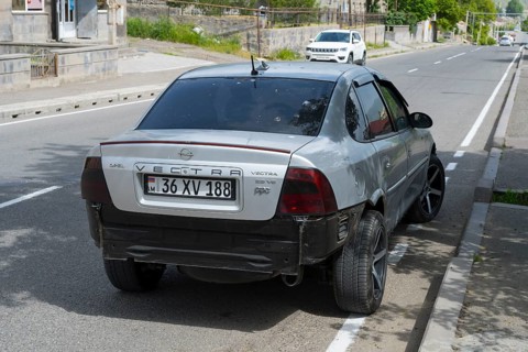 Grey Opel Vectra with modern rims and rear damage parked on the outskirts of the city, Armenia