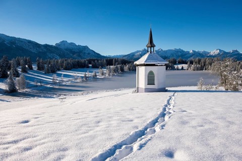 Chapel with footprints in the snow and a peaceful mountain landscape, Hegratsrieder See, near