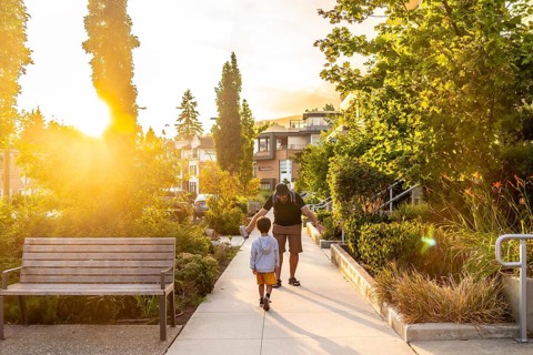 Father and son enjoying a leisurely stroll along a tree lined residential street in vancouver.