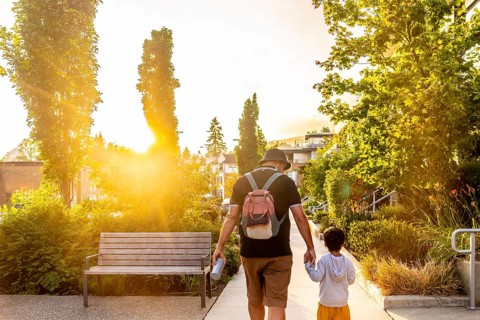 Father and son enjoying a leisurely stroll through a vancouver neighborhood at sunset, bathed in