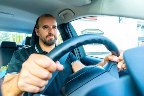 Bearded man driving a modern car in kamloops, british columbia, with a child visible in the back