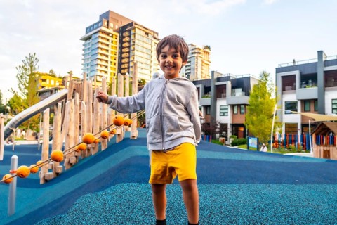 Smiling preschool child having fun in a colorful playground located in a residential area of