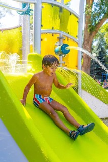 Happy child having fun sliding down a water slide at a colorful playground in kamloops, british