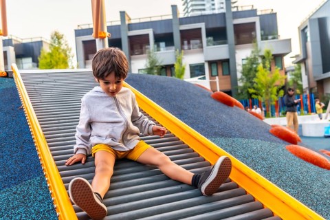 Preschool child having fun sliding down roller slide at playground in vancouver, british columbia,