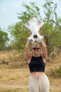 Woman holding a hippopotamus skull in the air, Botswana
