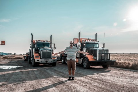 Trucker is proudly showing his two big orange trucks in hemlock grove boardwalk, a scenic rest area