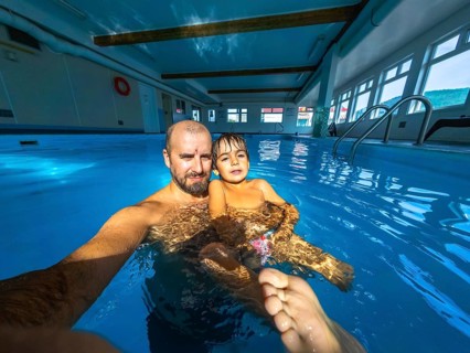 Father and son are taking a selfie while having fun and enjoying time together in a swimming pool