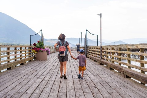 Mother and son walking hand in hand along a scenic wooden pier, surrounded by serene waters and