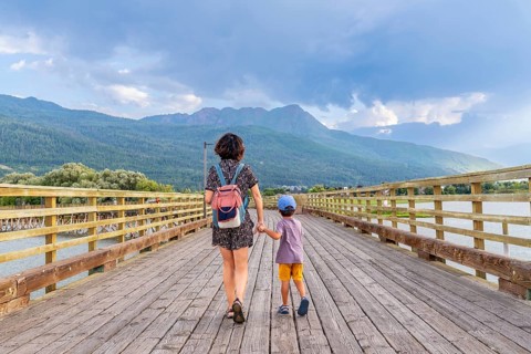 Mother and her son are enjoying a leisurely stroll across a long wooden pier, surrounded by the