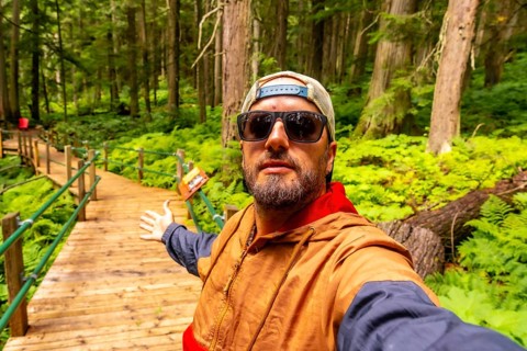 Hipster tourist taking a selfie while walking and showing the hemlock grove boardwalk in an ancient