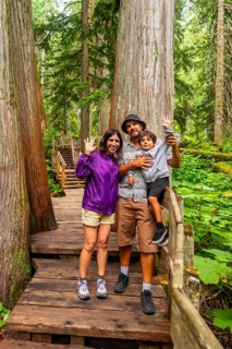 Tourists enjoying a summer hike waving at the camera on the giant cedars boardwalk trail in mount