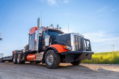 Powerful big rig semi truck with empty flatbed trailer parked on hemlock grove boardwalk in the