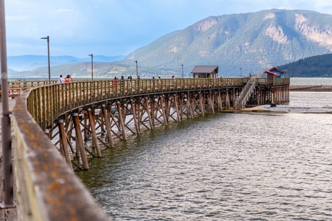Tourists are walking on the long wooden pier that curves across the shuswap lake in salmon arm,