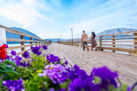 Tourists walking on a wooden pier adorned with vibrant flowers, enjoying the scenic beauty of
