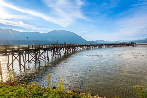 Long wooden pier stretching into the calm waters of shuswap lake in salmon arm, british columbia,