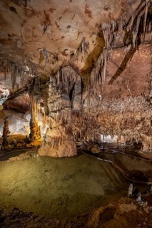 Stalactites and stalagmites, rock formations in a stalactite cave with water basin, Grotta del