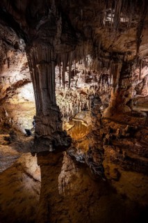 Stalactites and stalagmites reflected in water basins, rock formations in a stalactite cave, Grotta